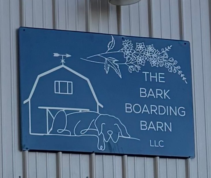 The painted sign on the barn: a drawn barn, weathervane and sleeping dog.