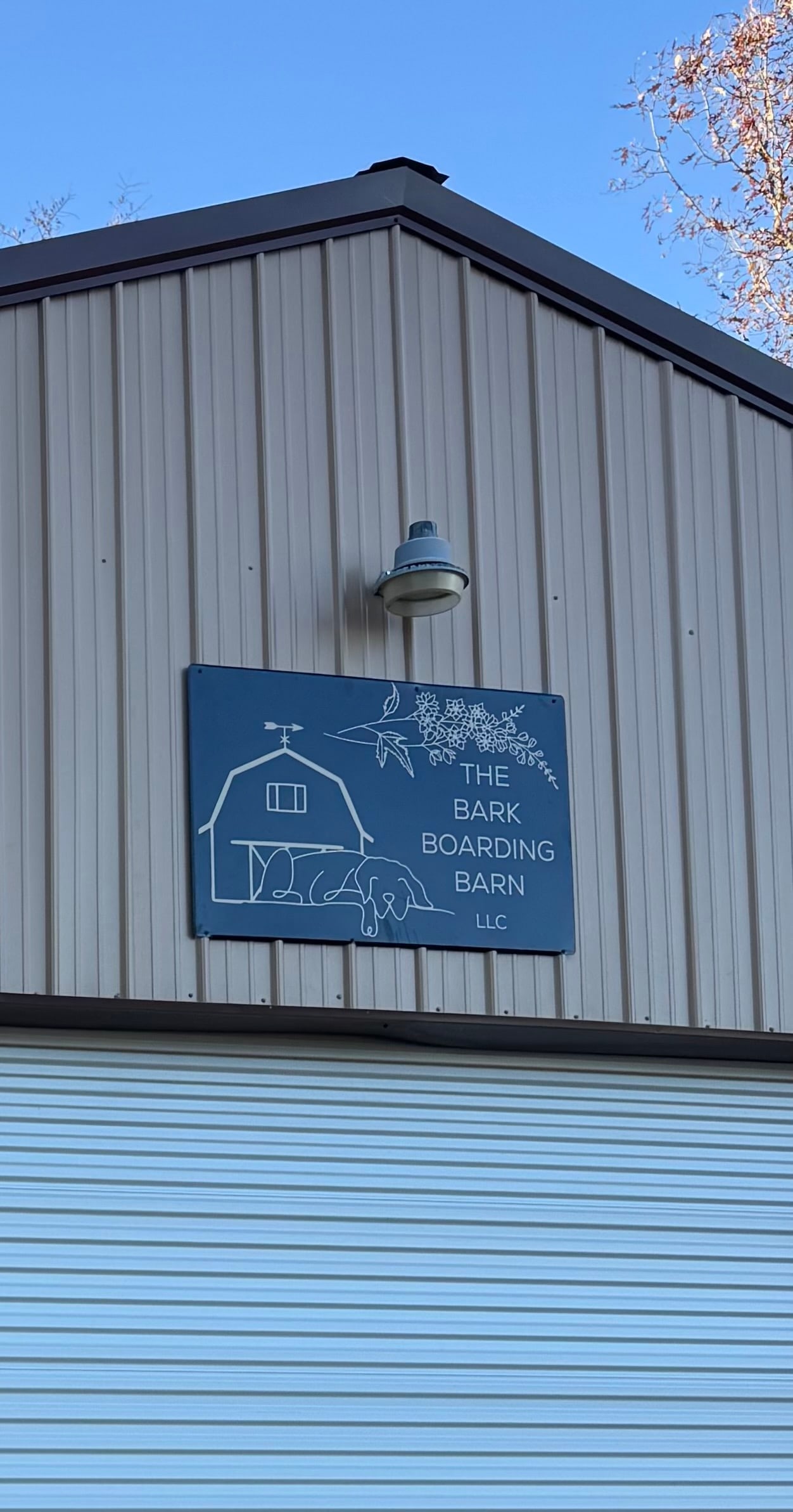 The barn's painted sign above the door: a drawn barn, weathervane and sleeping dog.
